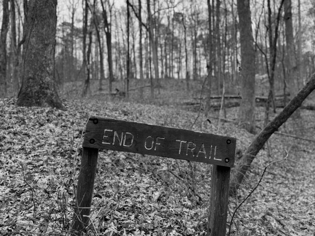 sign in the woods that reads "End of trail"