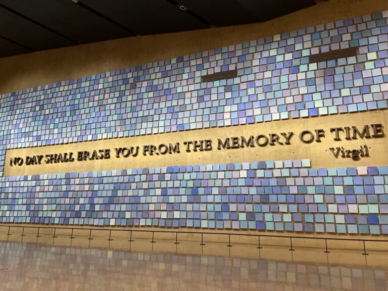 No day shall erase you from the memory of time. Virgil The photo depicts this quotation on a wall at the 9/11 memorial in New York.